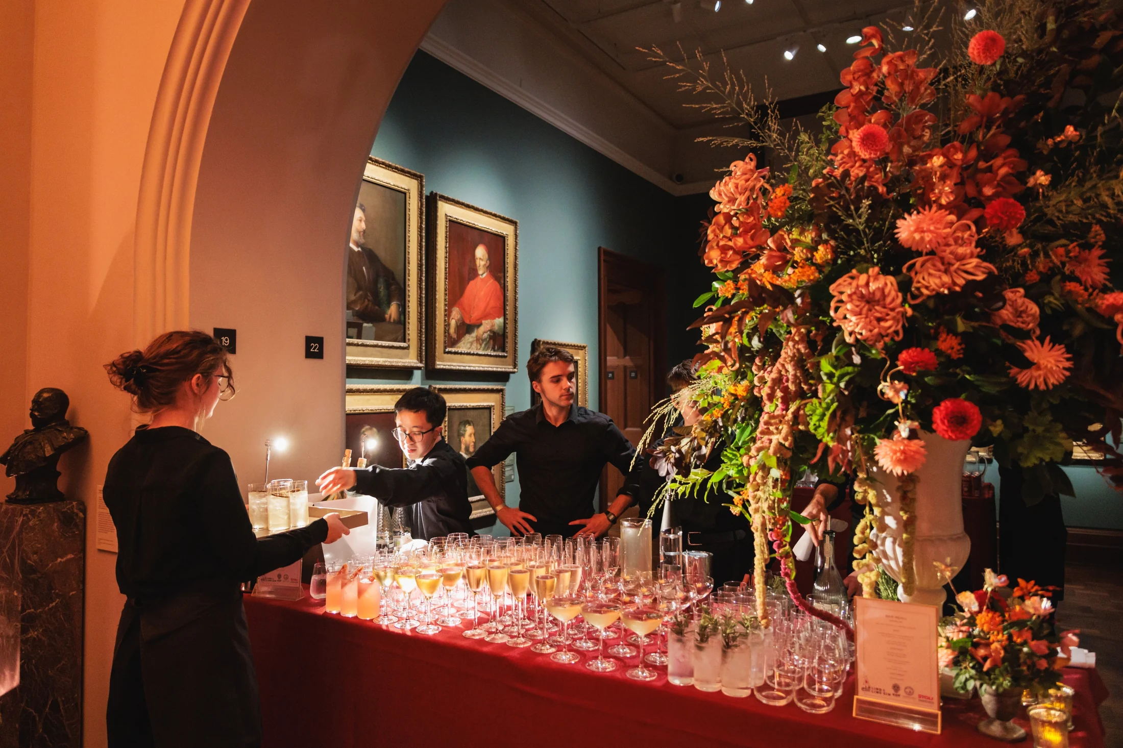 Guests and drinks service surrounded by floral installations inside the National Portrait Gallery